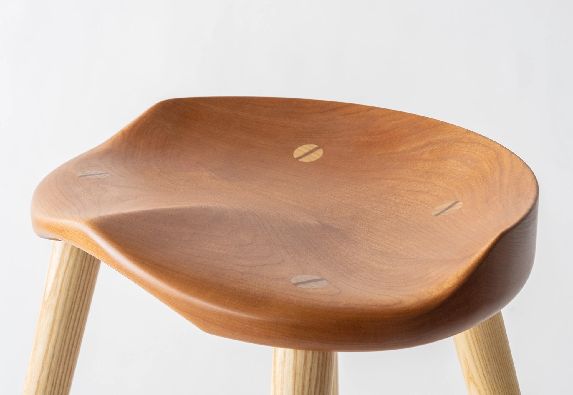 Wooden stool with a light brown seat and legs on a white background