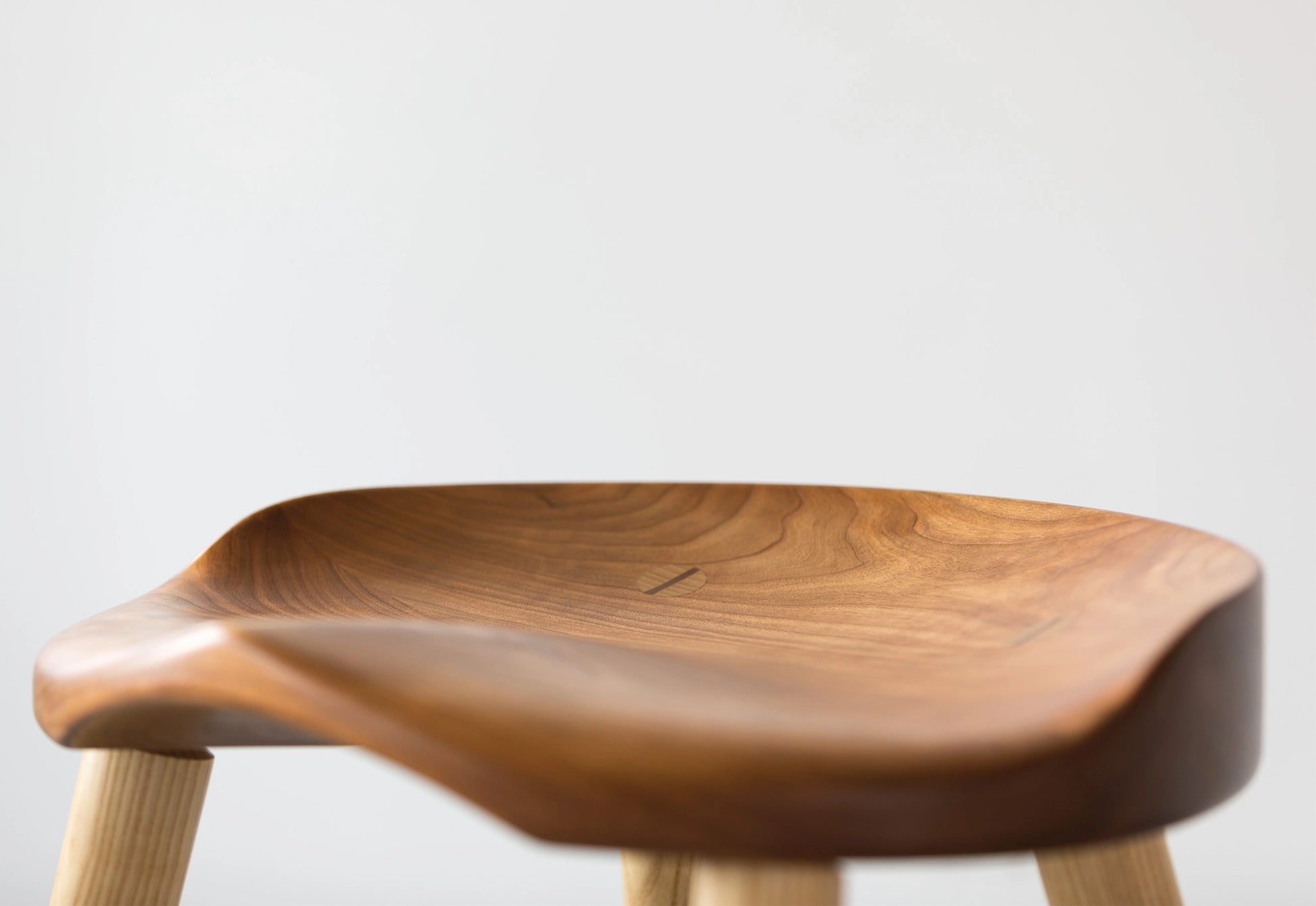 Wooden stool with a light brown finish on a white background