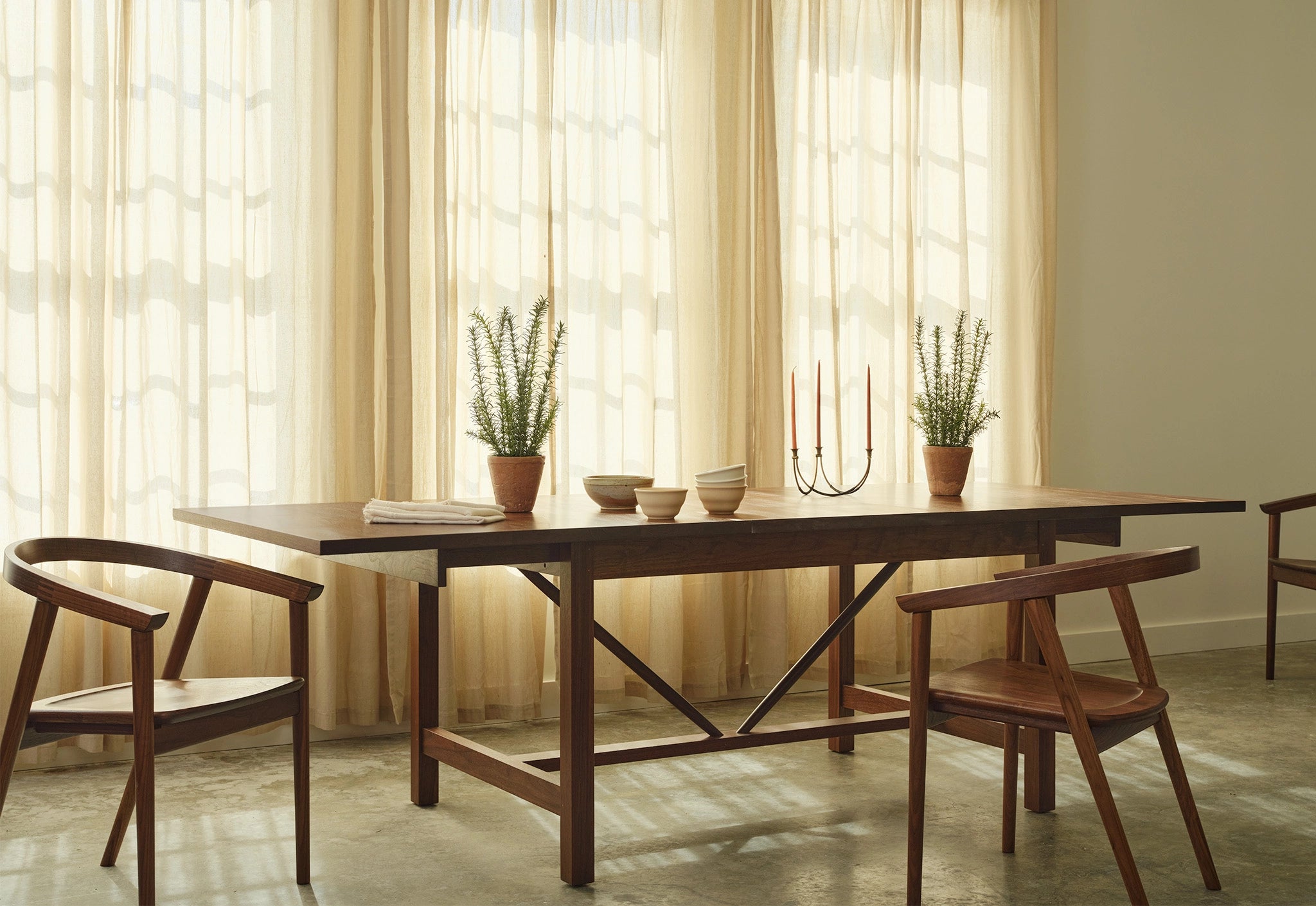 Wooden dining table with chairs in a room with light curtains