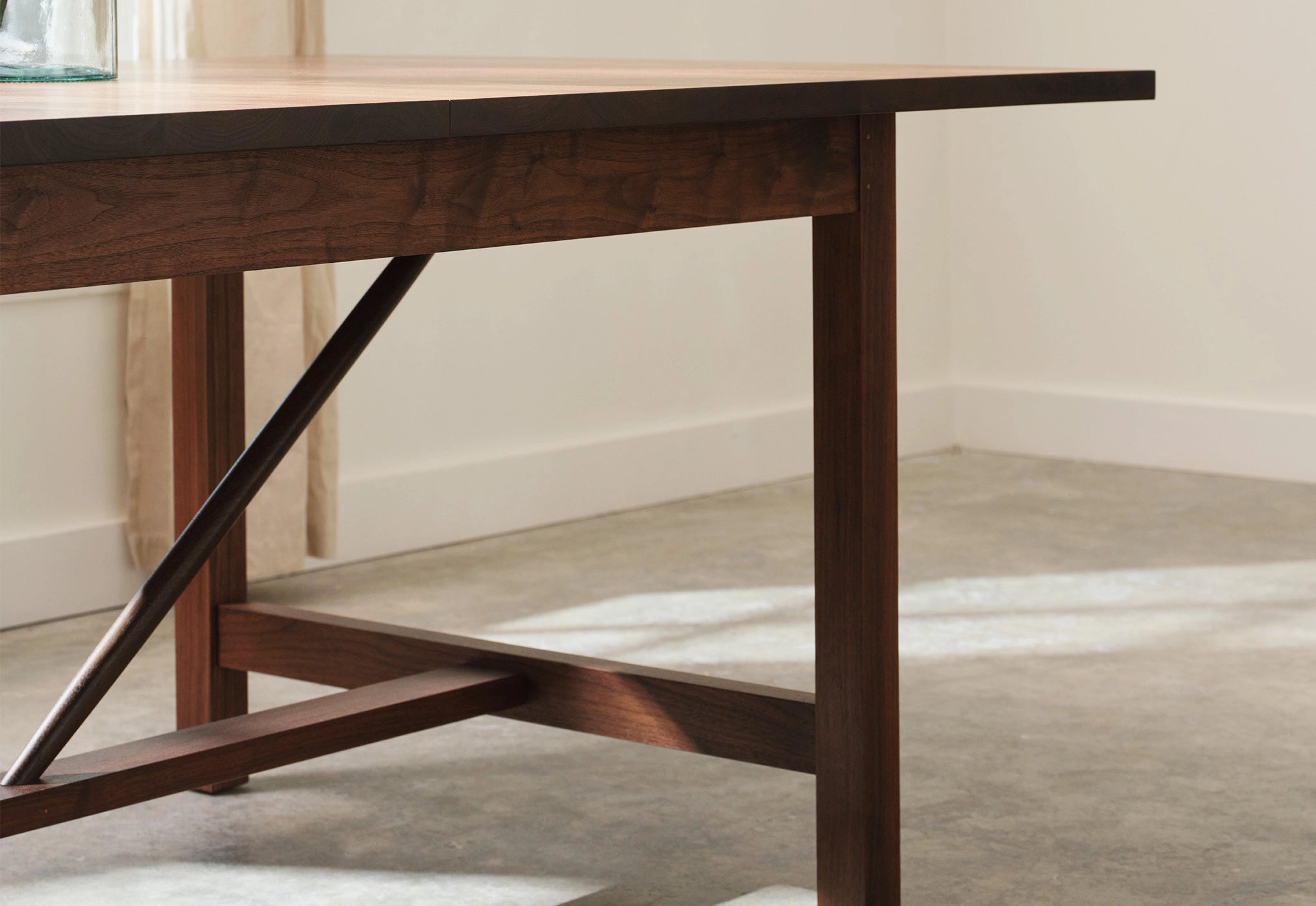 Wooden dining table with a minimalist design in a room with light-colored flooring.
