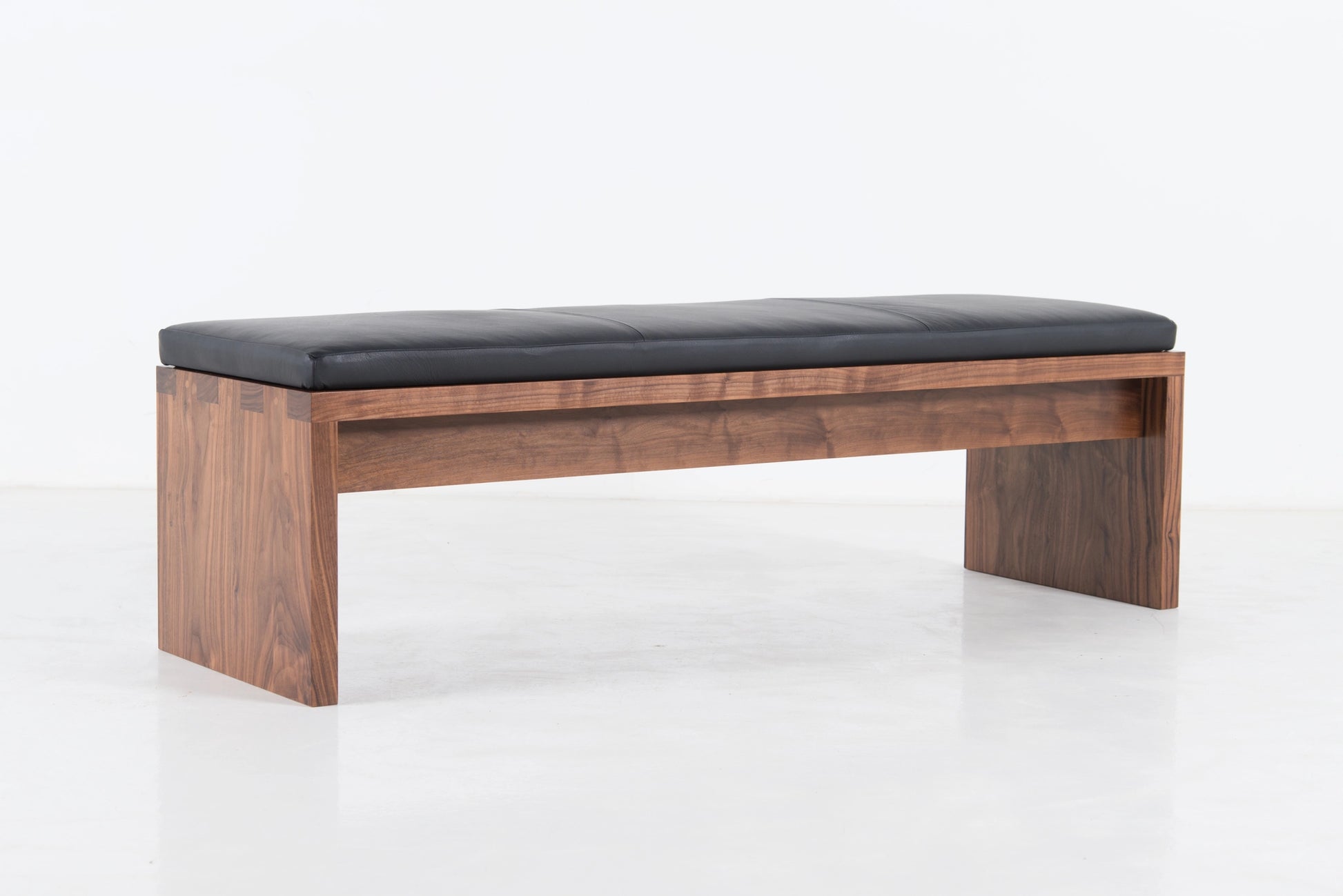 Wooden bench with black cushion on a white background