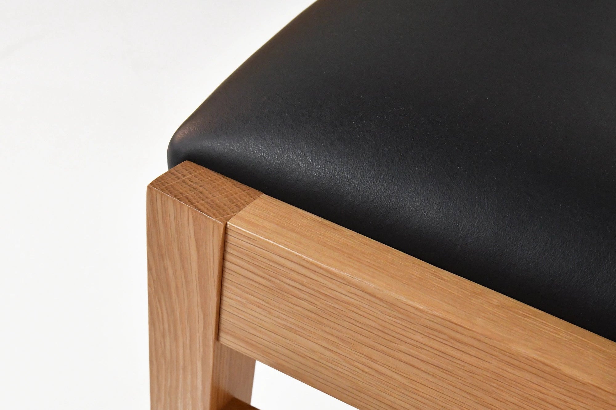 Wooden chair with black cushion on a white background