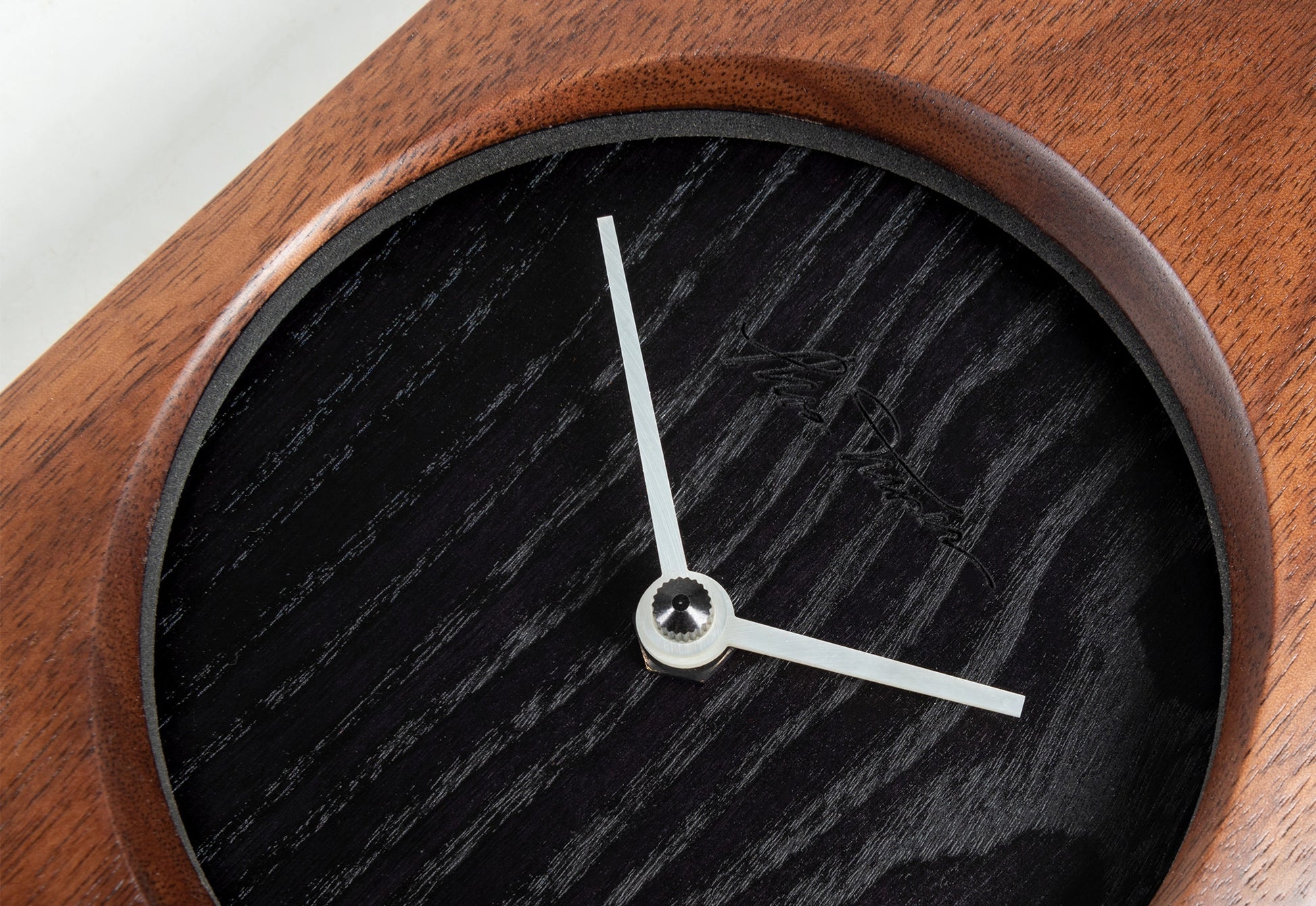 Wooden clock with black clock face and white hands on a white background