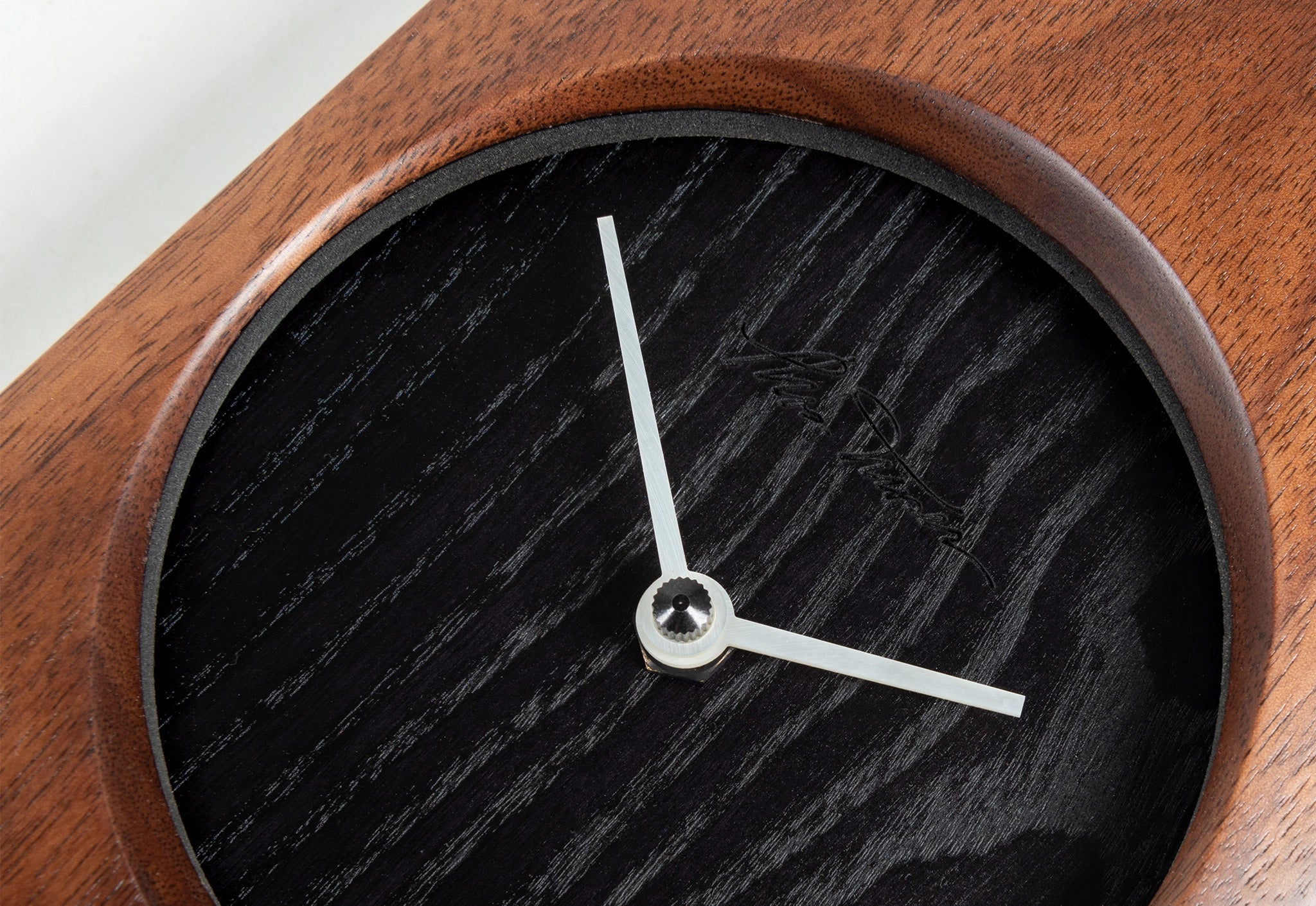 Wooden clock with black clock face and white hands on a white background