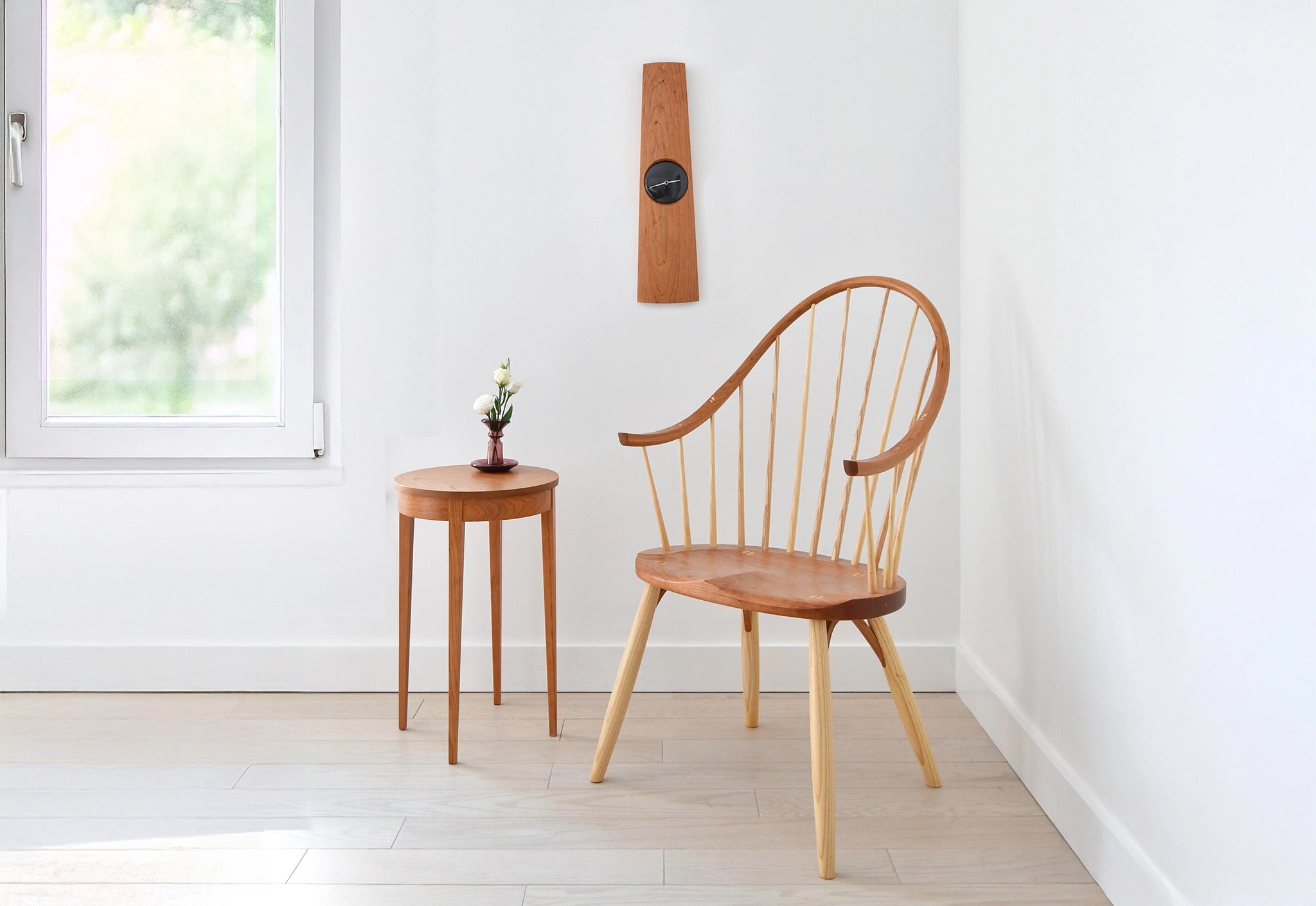 Wooden chair and side table in a minimalistic room with a window.