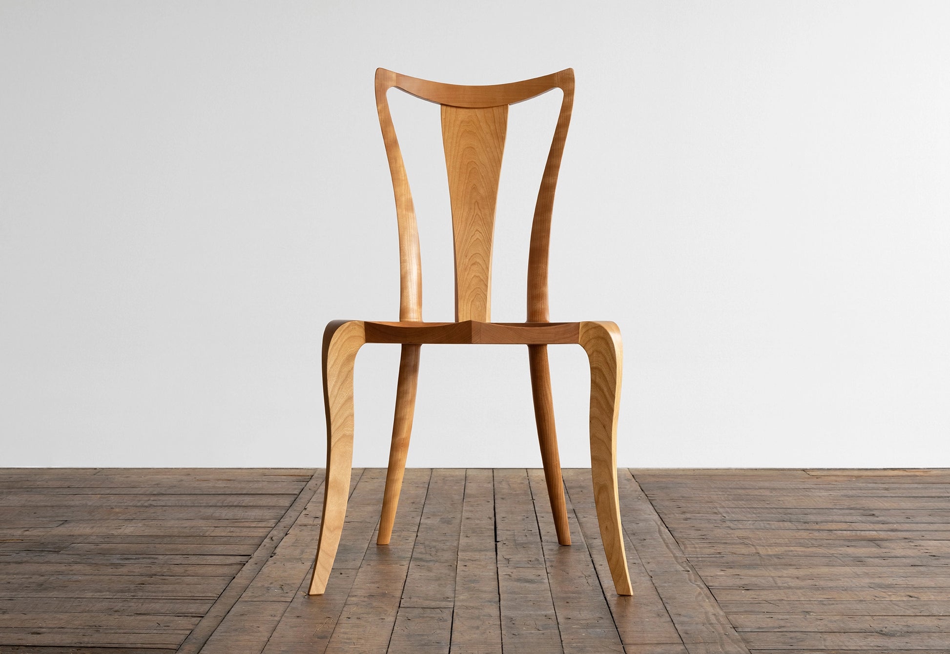 Wooden chair on a wooden floor with a white wall background