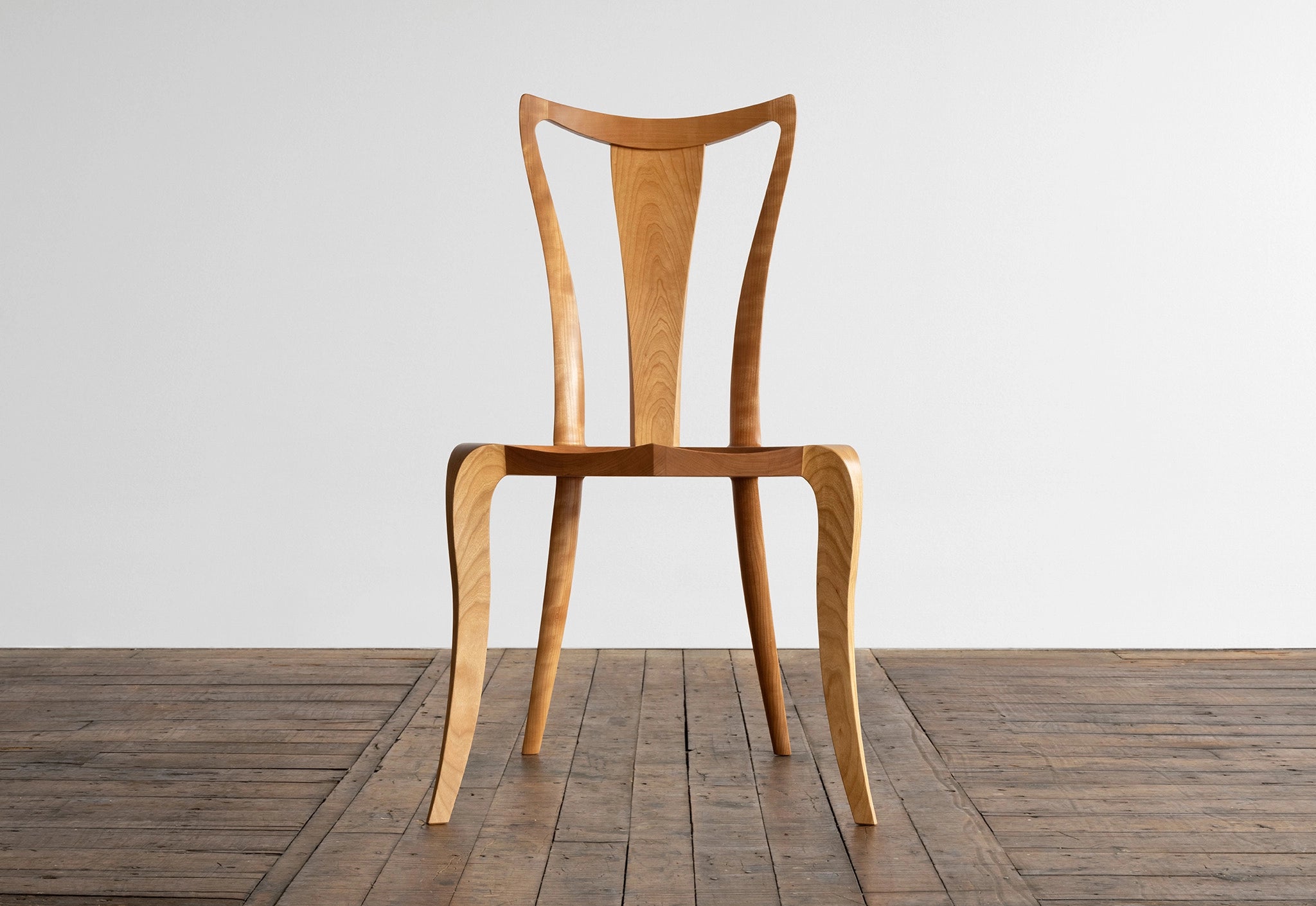 Wooden chair on a wooden floor with a white wall background