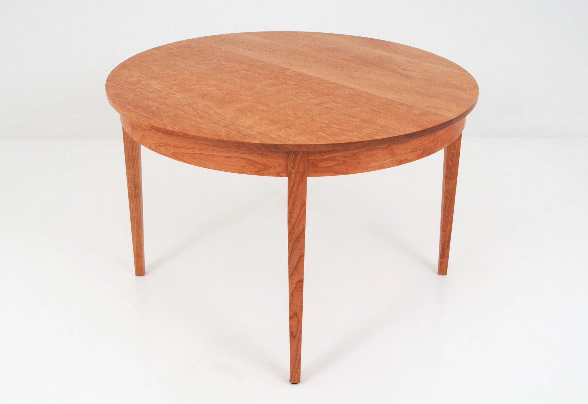 Wooden round table with a single extension leaf on a white background