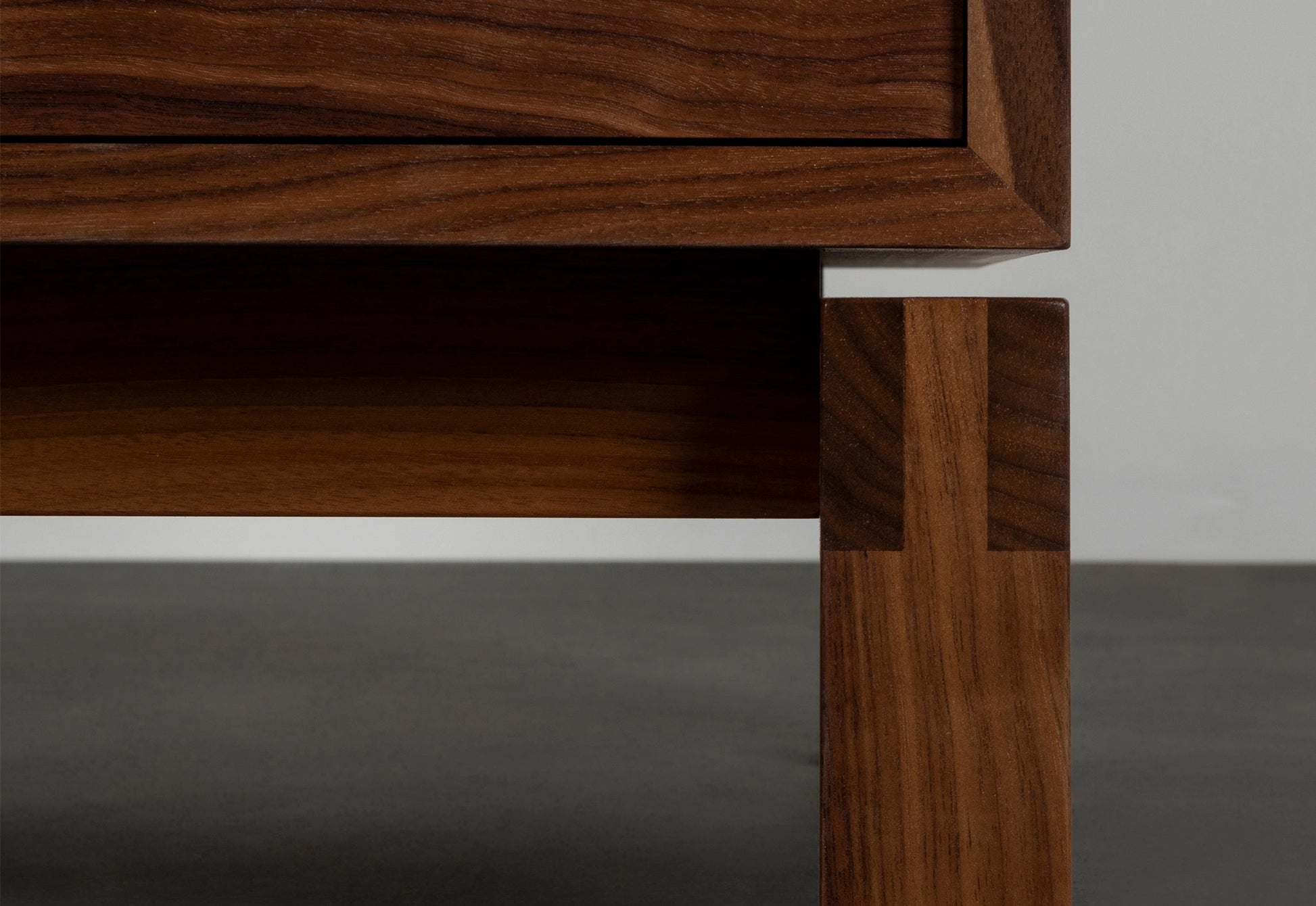 Close-up of a wooden drawer and leg on a gray background
