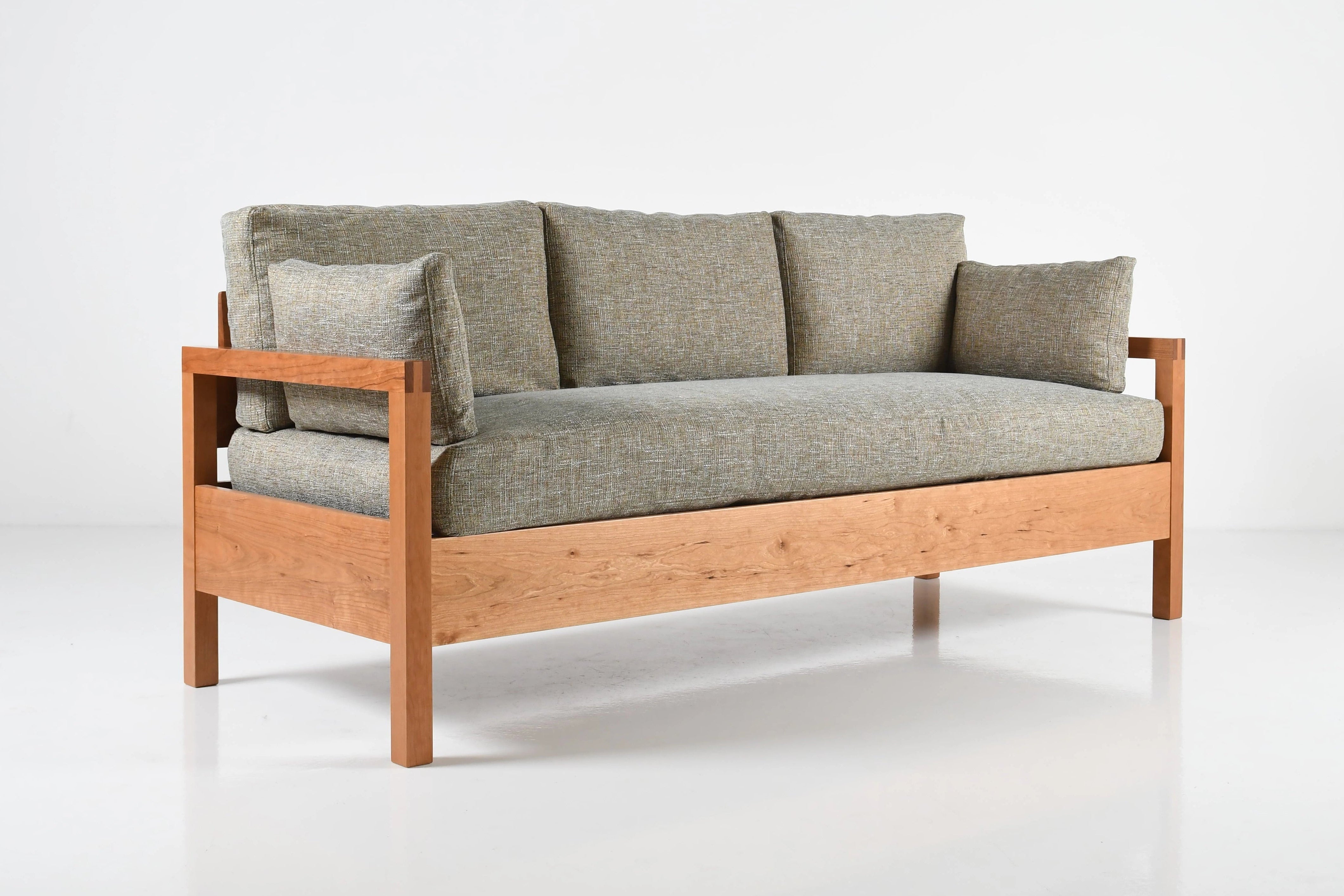 Sofa with wooden frame and gray cushions on a white background