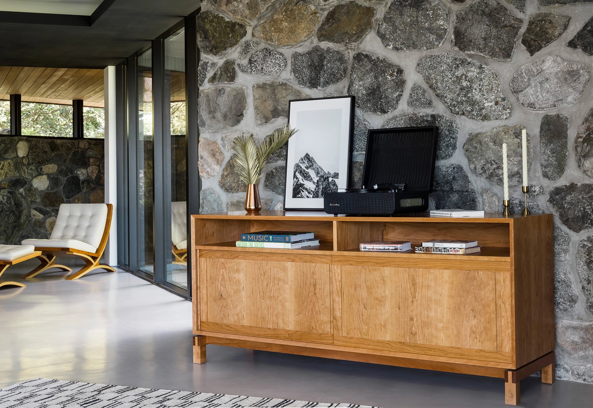 Wooden sideboard against a stone wall with a television and decor items.
