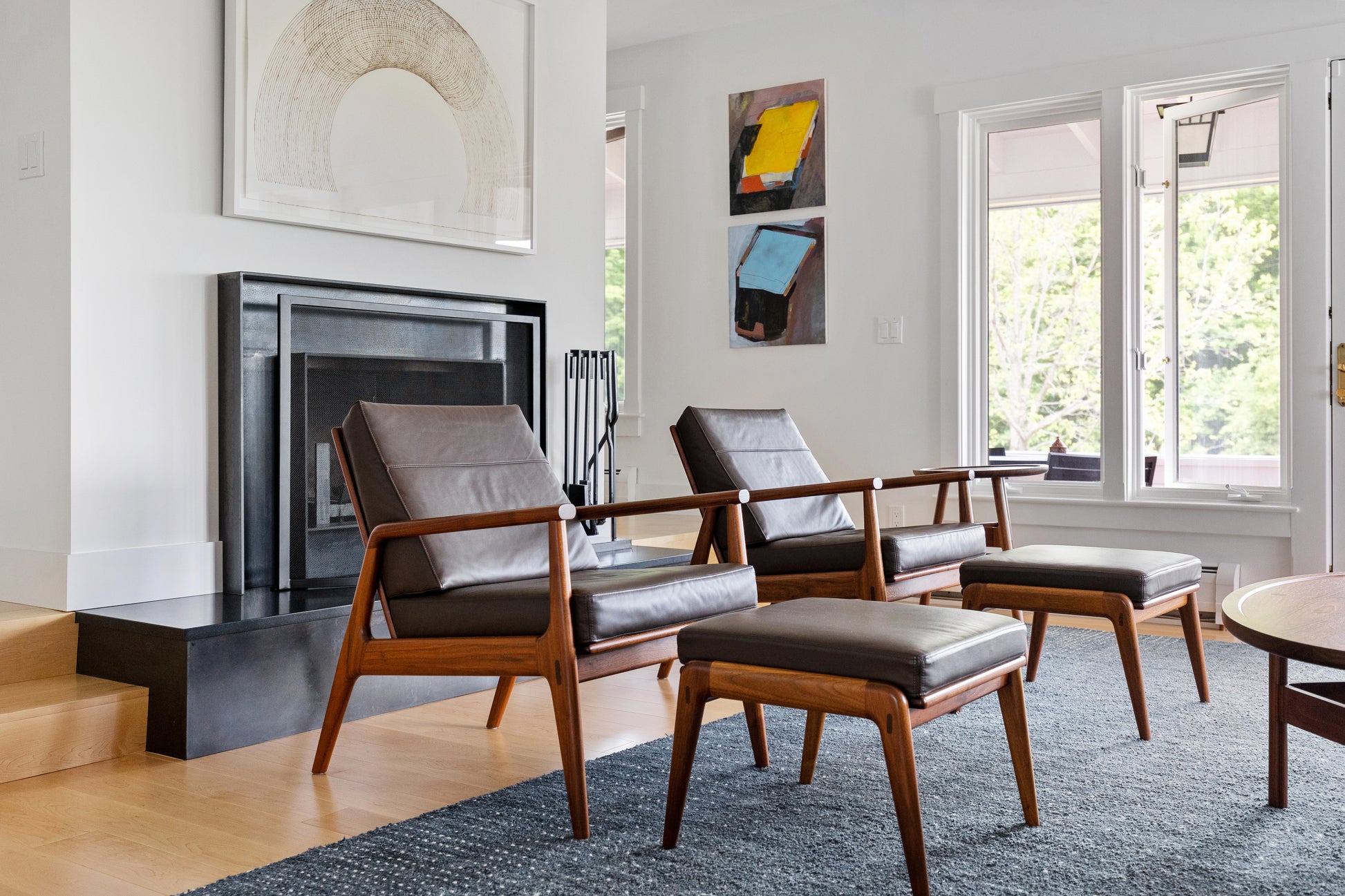 Modern living room with leather chairs, ottomans, and a fireplace.