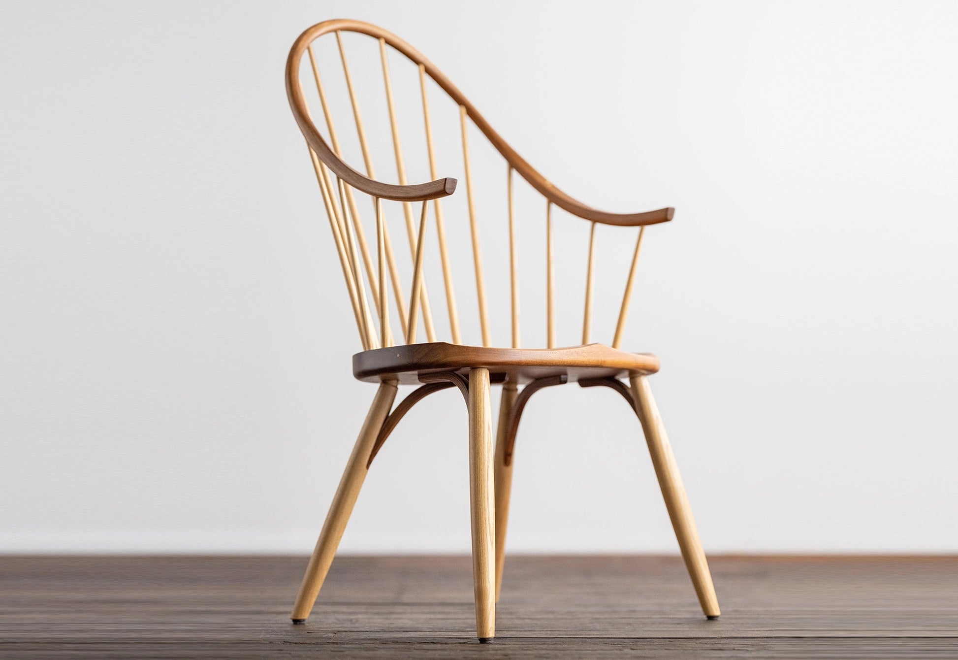 Wooden chair with curved backrest on a wooden floor against a white wall