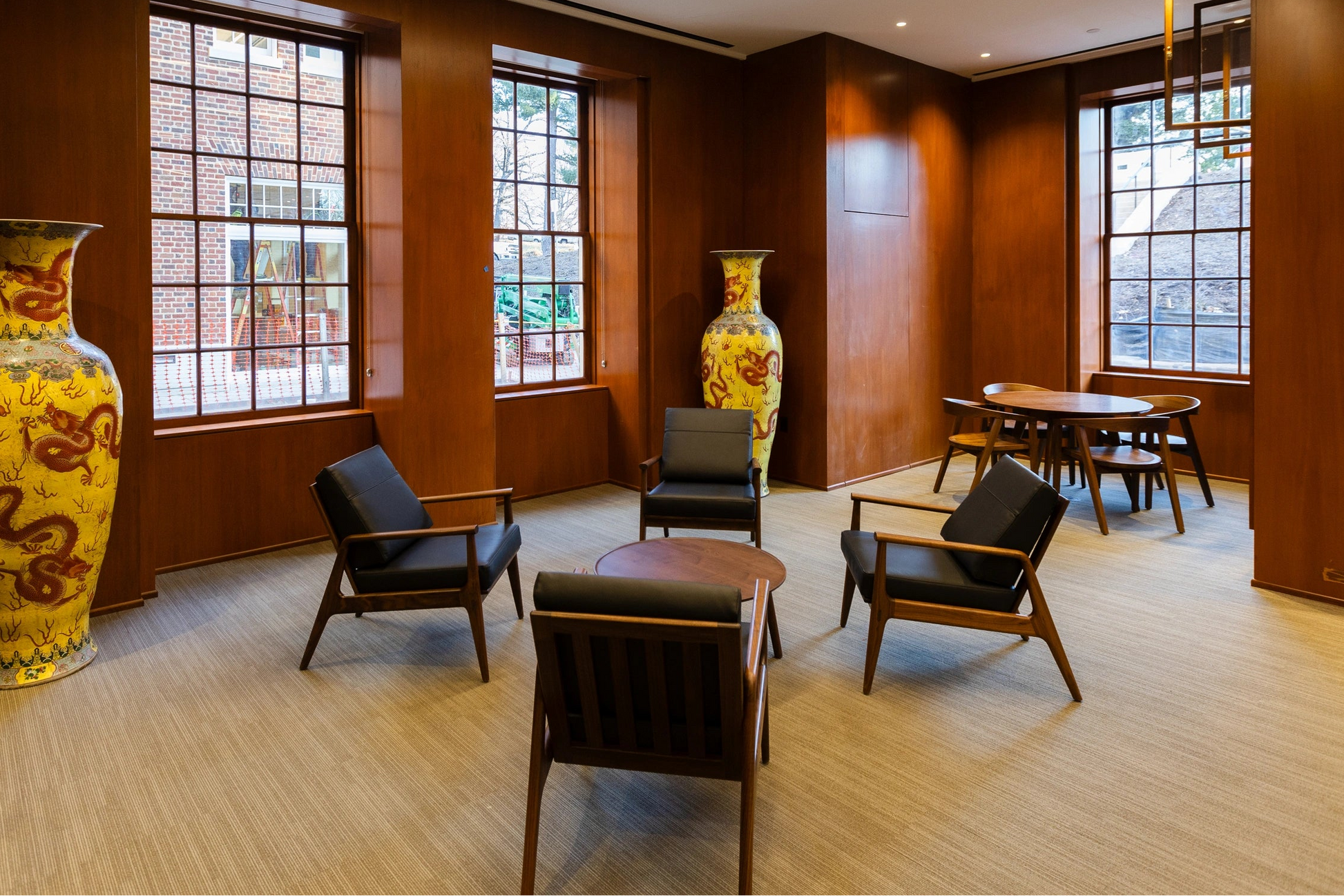 Modern interior with large yellow vases, chairs, and a dining table.