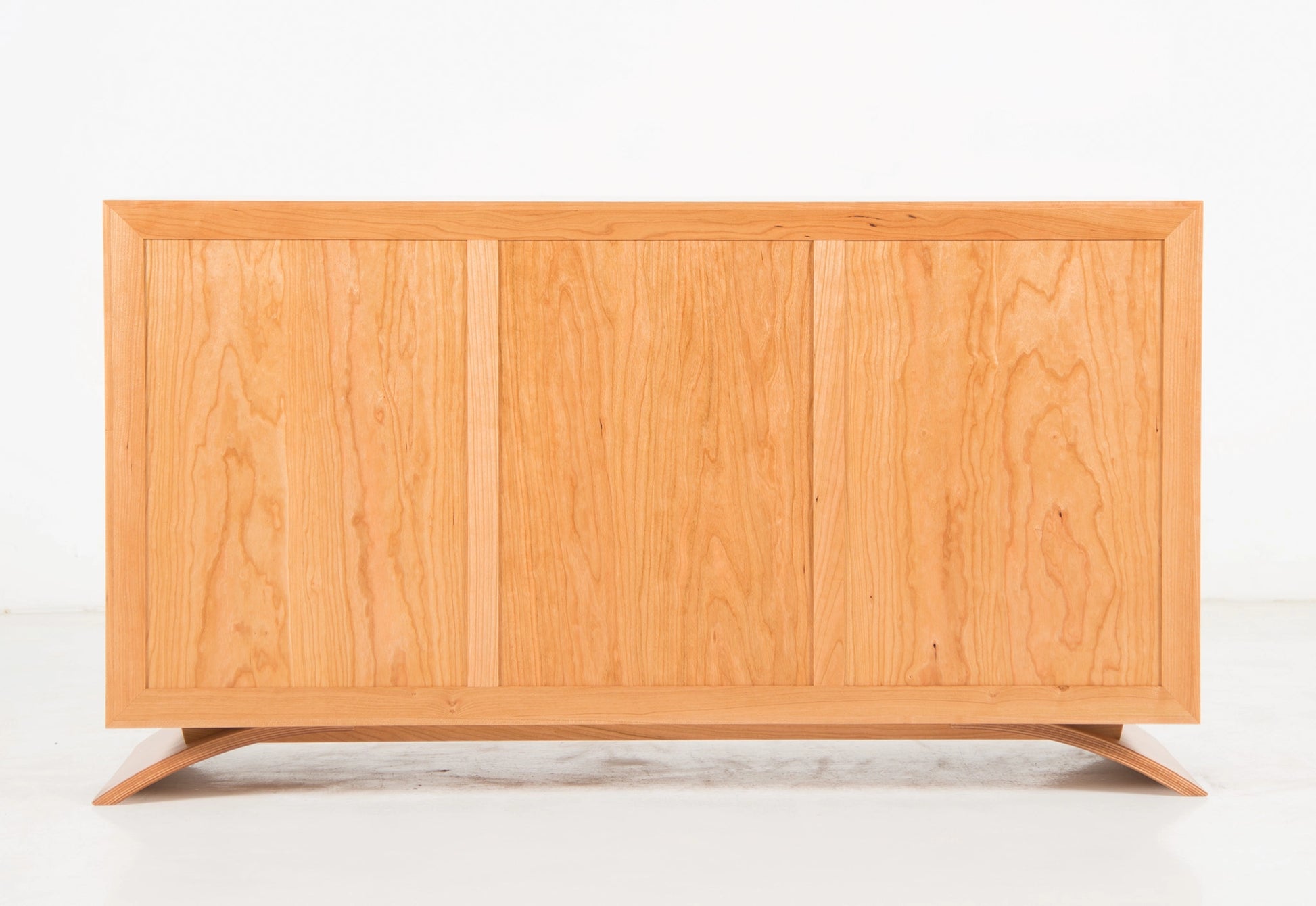 Back of a wooden dresser with a light finish on a white background