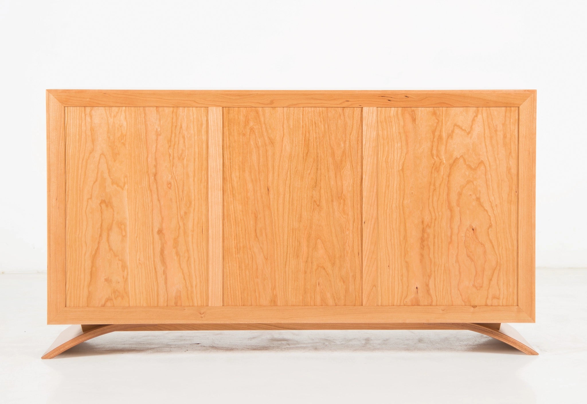 Back of a wooden dresser with a light finish on a white background