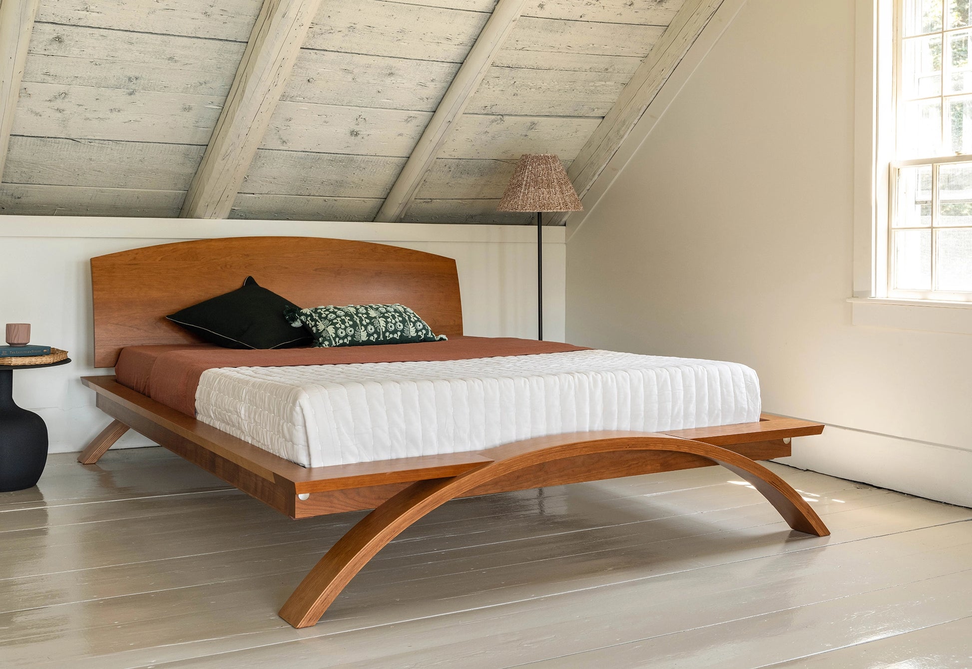 Wooden bed with white bedding in a room with wooden floor and ceiling.
