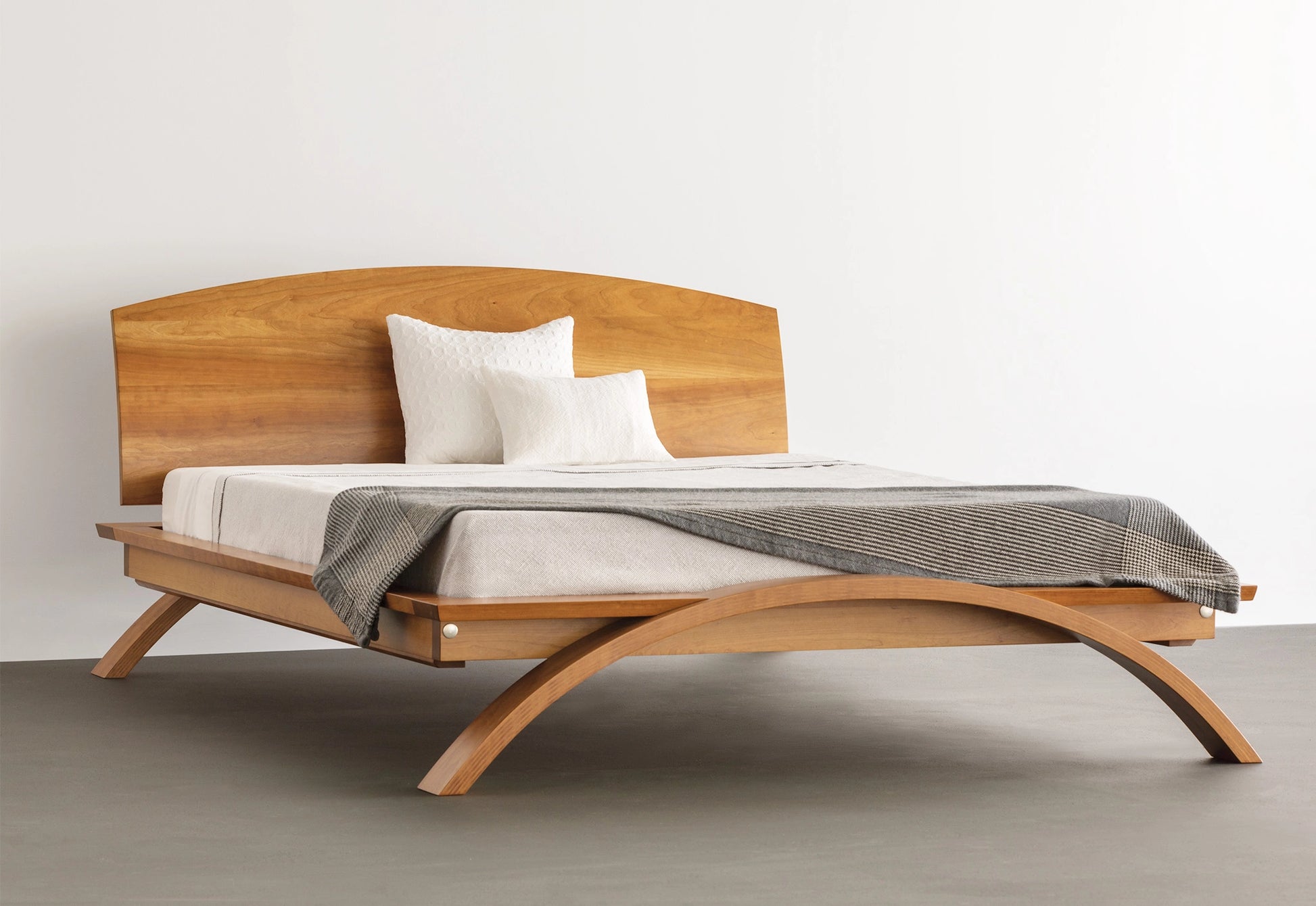 Wooden bed with a headboard and bedding on a plain background