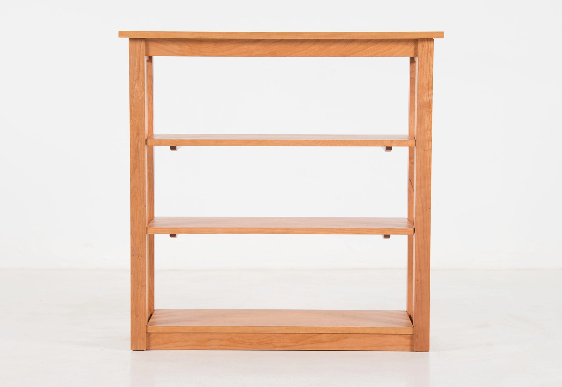 Wooden bookshelf with three shelves on a white background
