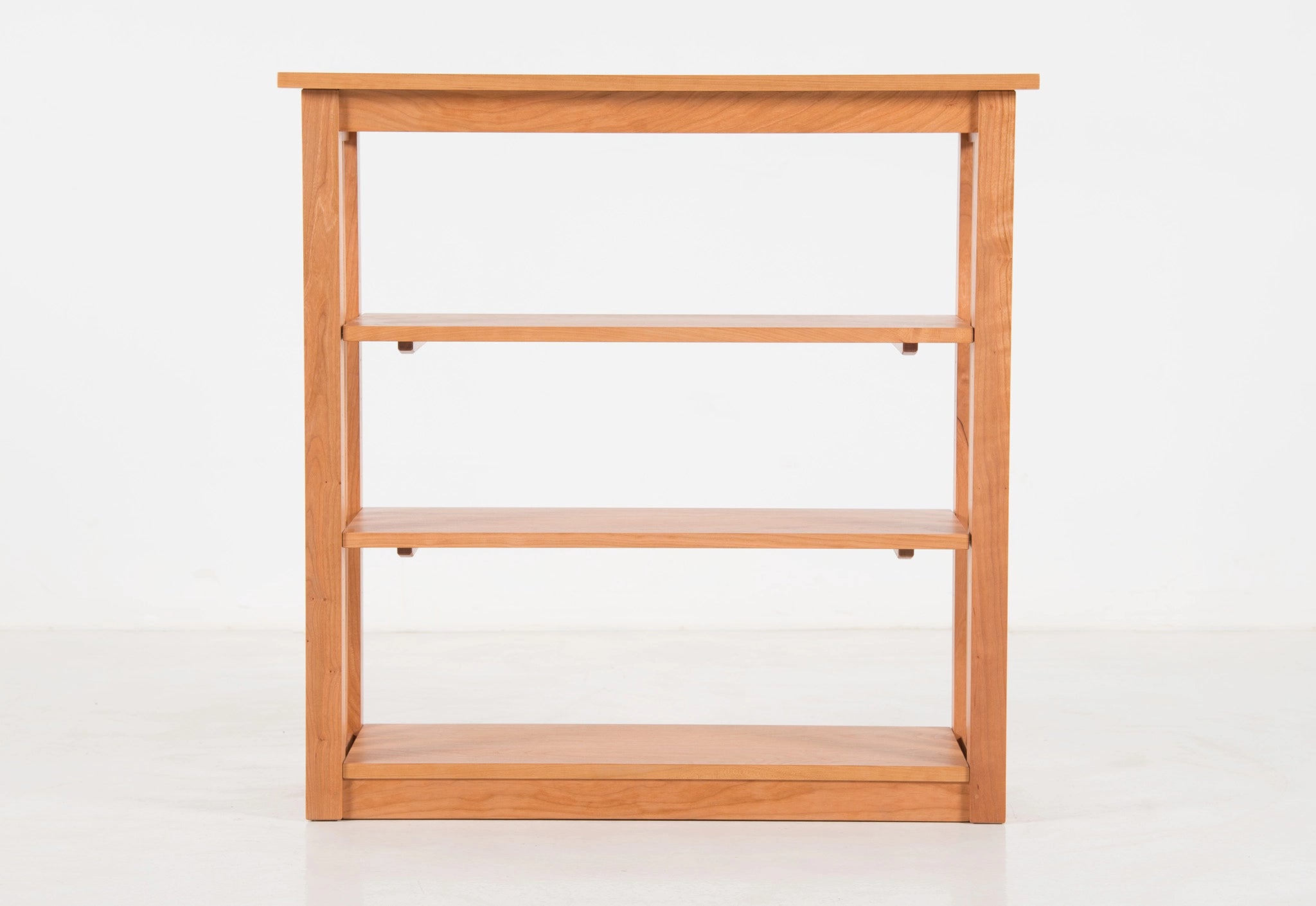 Wooden bookshelf with three shelves on a white background