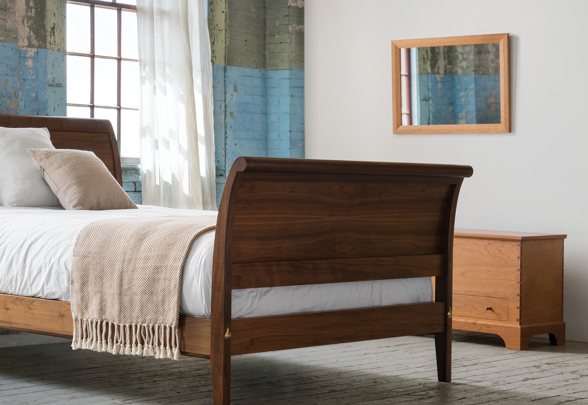 Wooden bed with white bedding and a beige blanket in a bedroom setting.