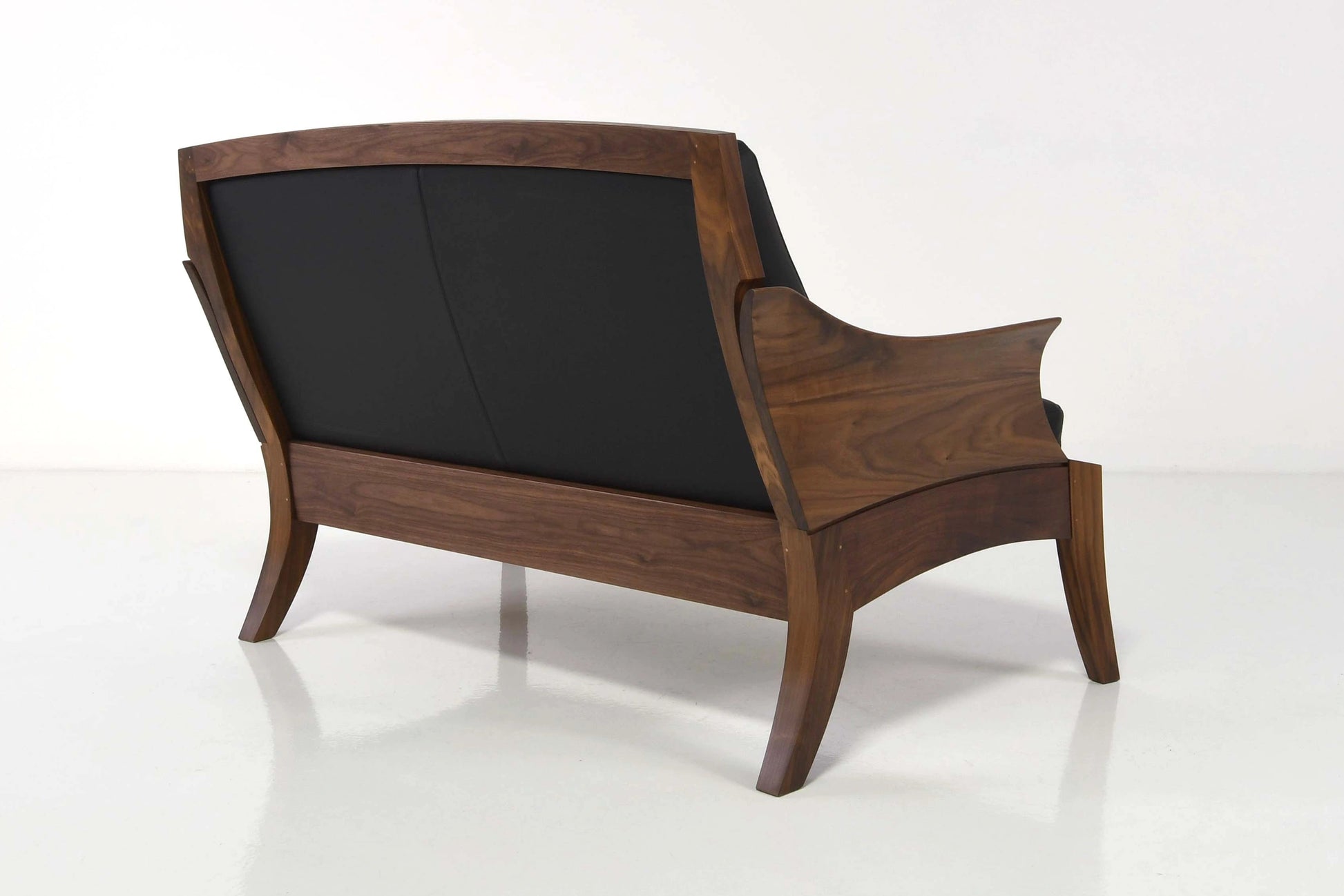 Wooden armchair with black cushion on a white background