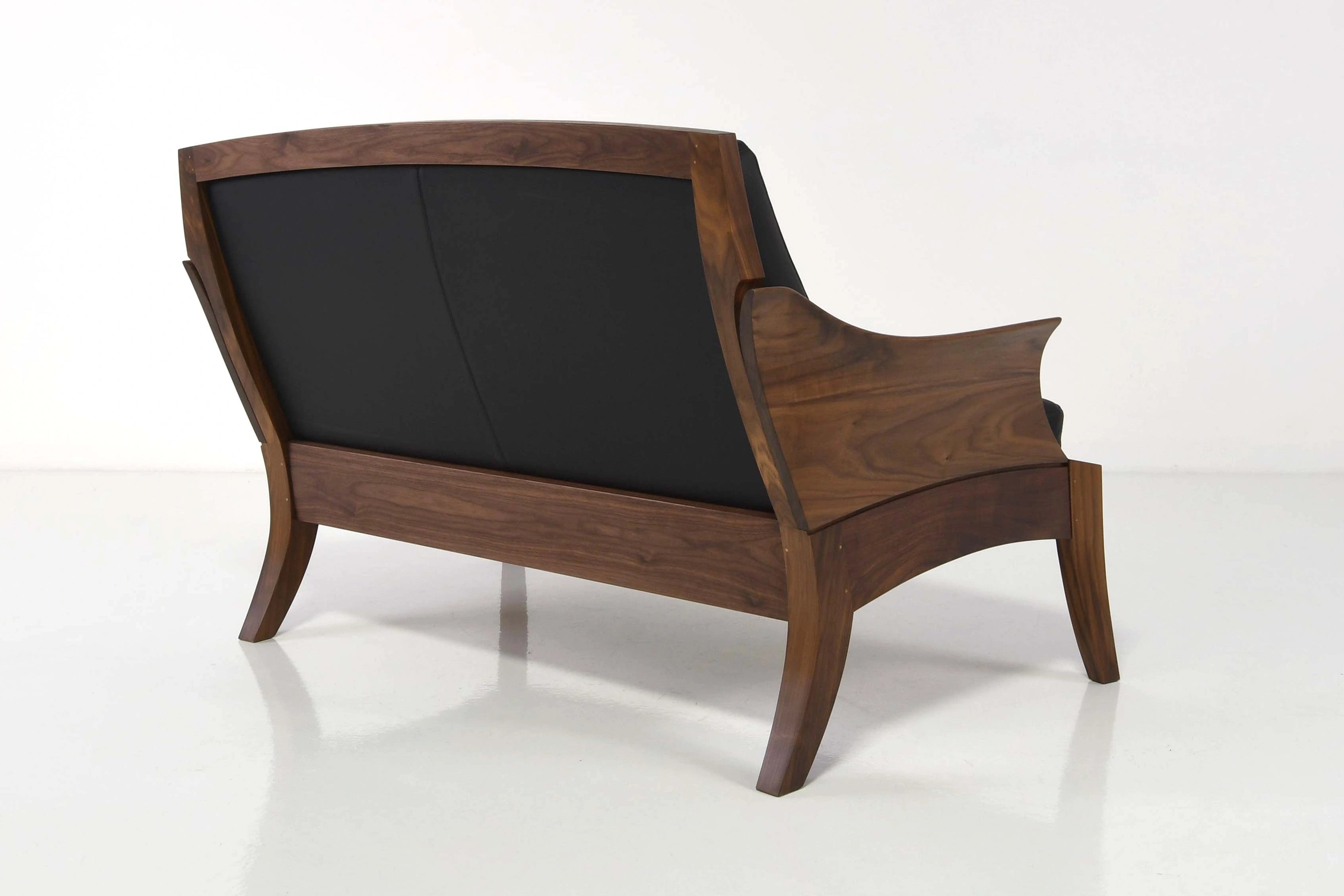 Wooden armchair with black cushion on a white background