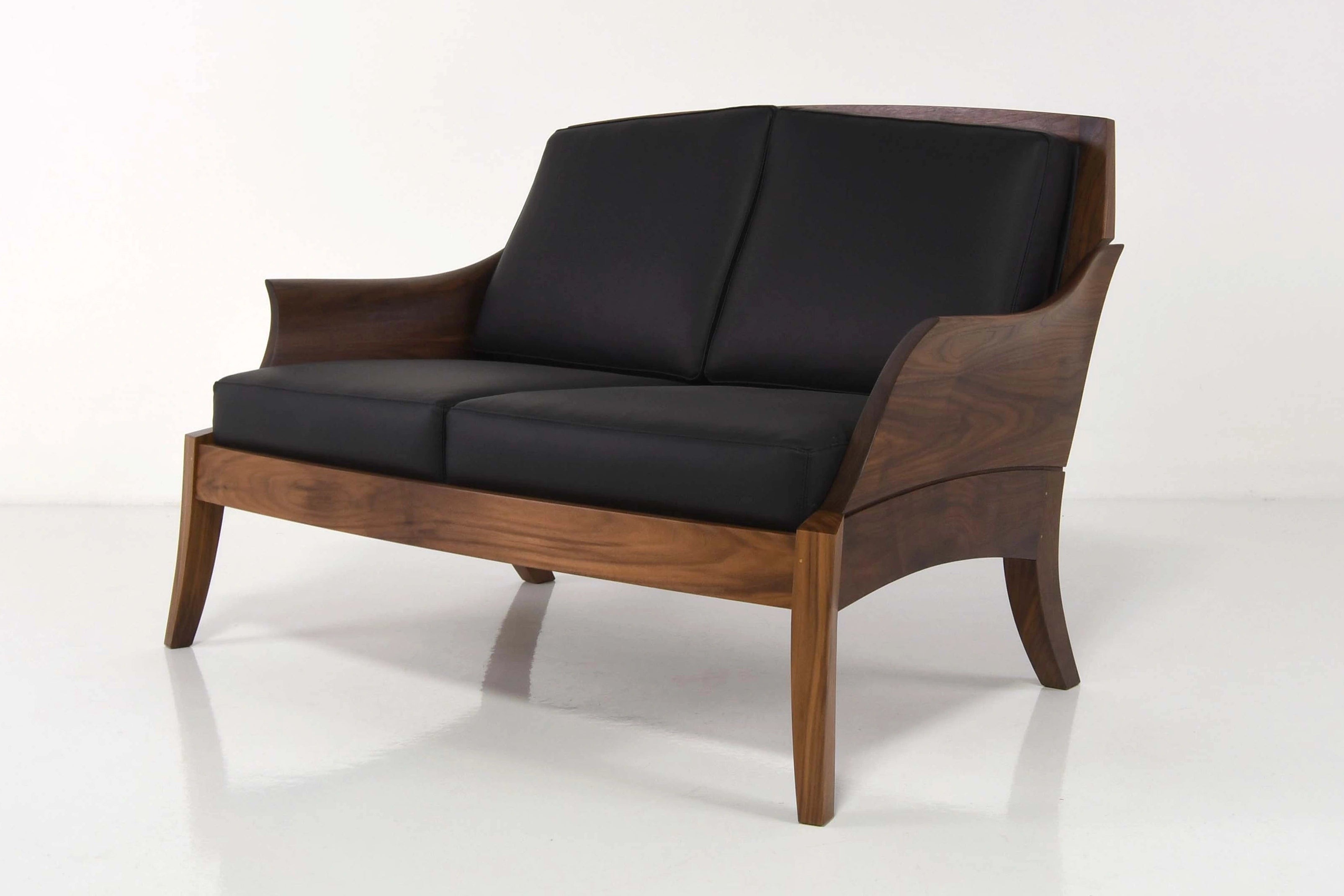 Modern two-seater sofa with black cushions on a white background