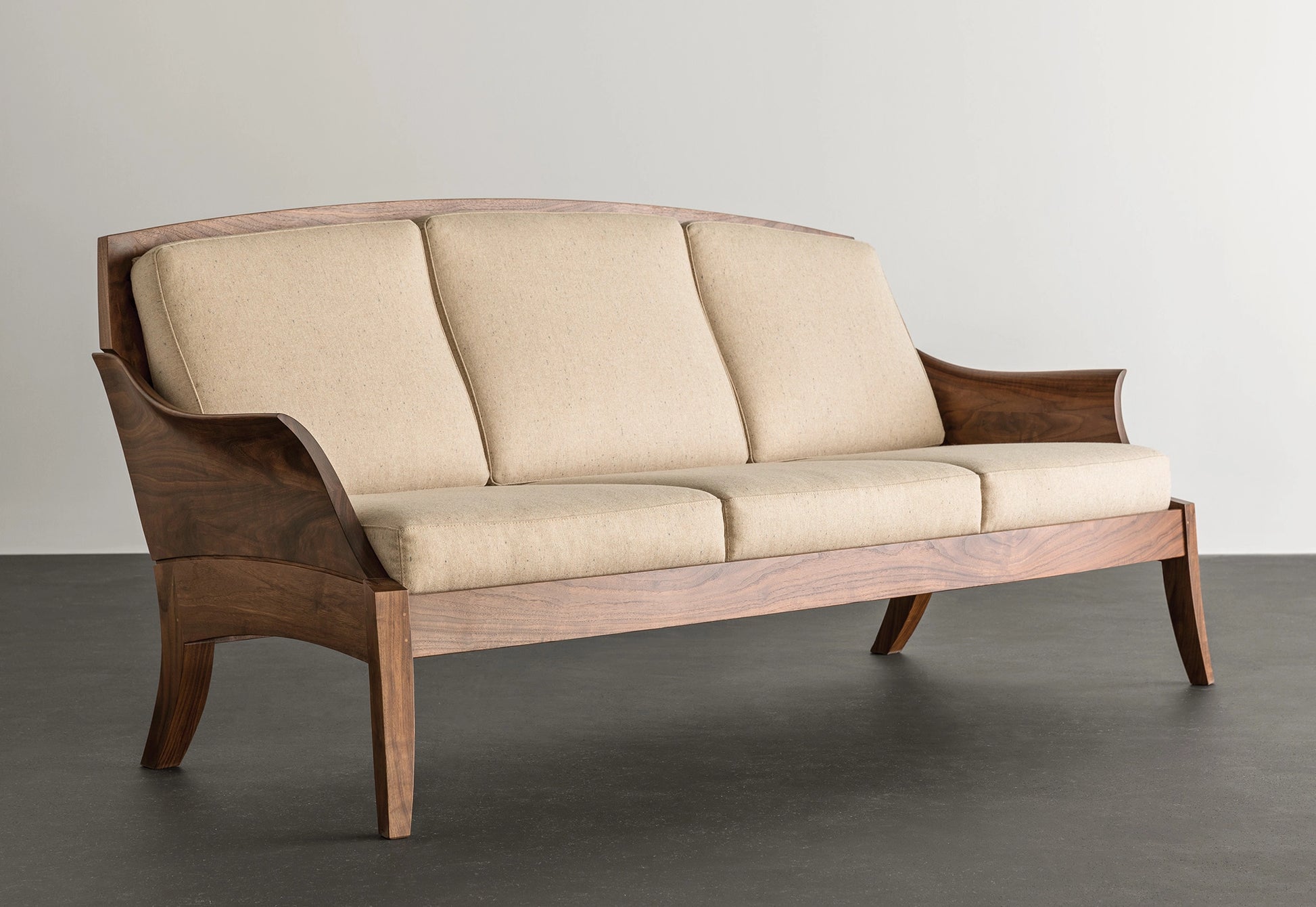 Beige sofa with wooden frame on a gray floor and light gray background