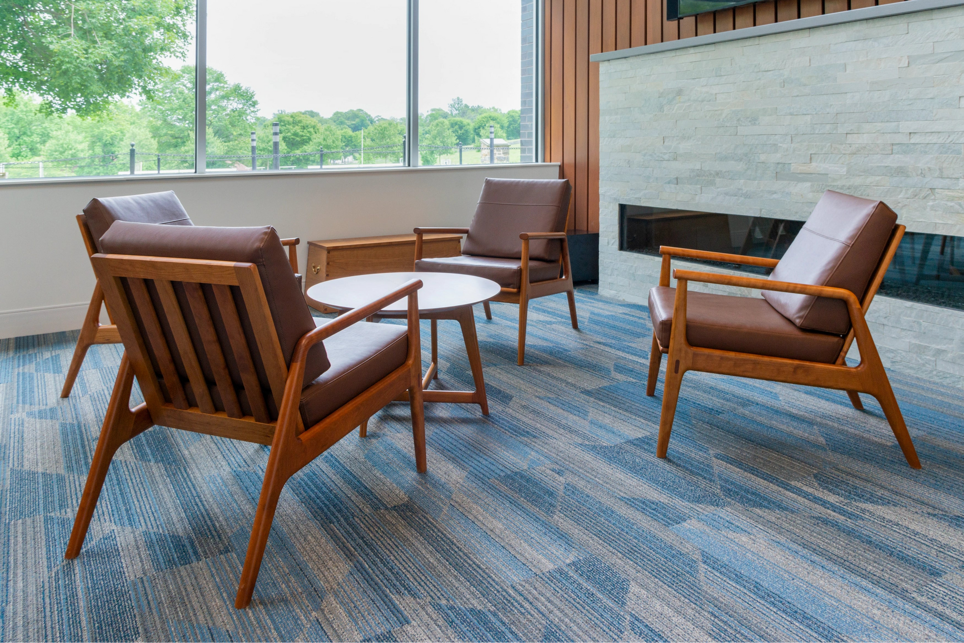 Modern lounge area with wooden chairs, a small table, and a fireplace.