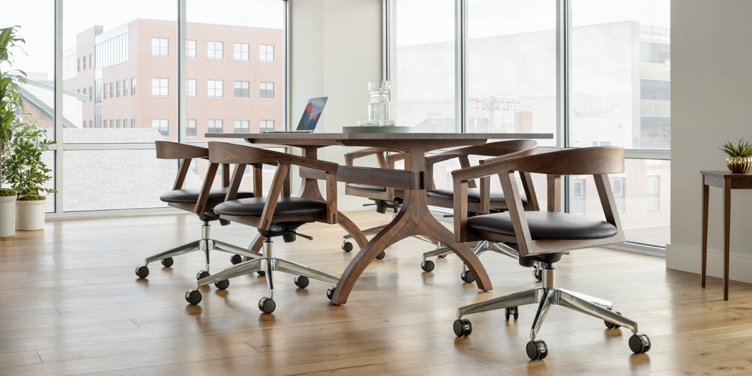 Office space with large windows, Wishbone trestle table in walnut with 6 NYPL branch swivel chairs seated around the table. Square minimus table in walnut with potted plant on right