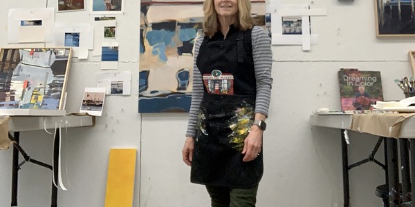 woman standing in the middle of art studio surrounded by paintings on the wall