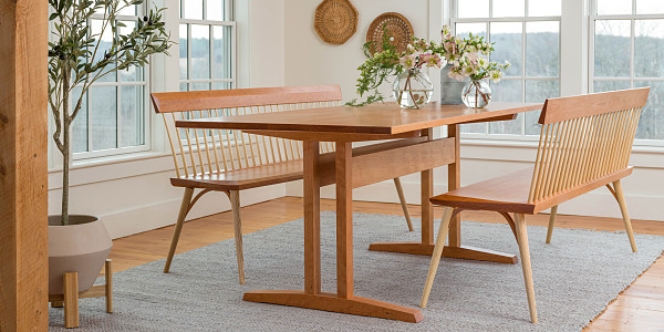 Wooden dining room table with two elongated chairs.