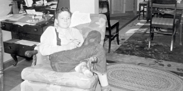Young Tom Moser sitting in chair in living room