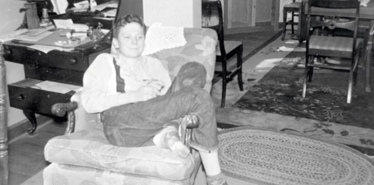 Young Tom Moser sitting in chair in living room