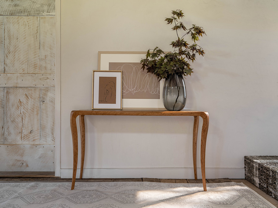 Pasadena hall table in cherry with framed artwork and a vase of greenery on the table top