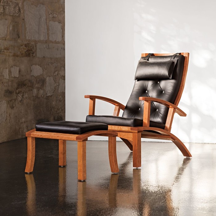 Lolling chair and ottoman in cherry with black leather in a studio setting