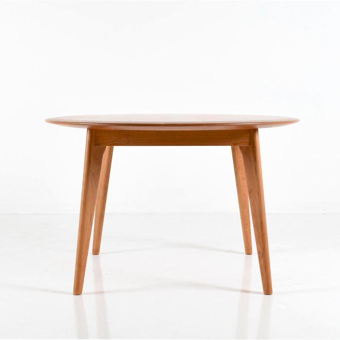 Unity Table with round top in cherry wood on a white background.