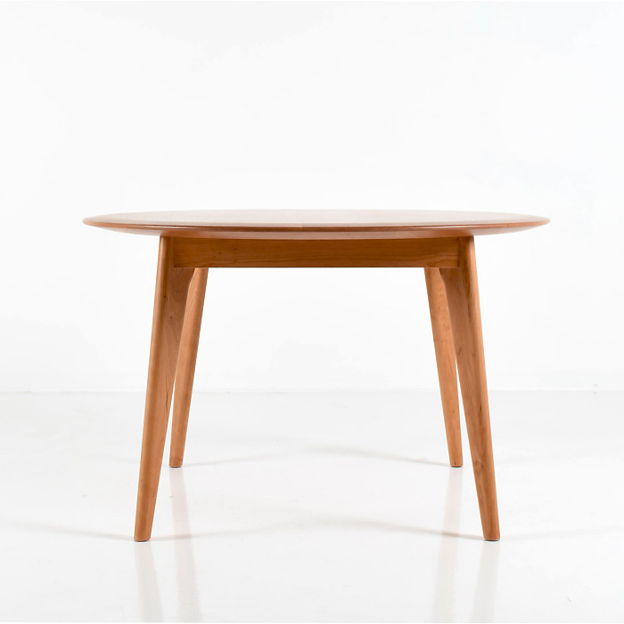Unity Table with round top in cherry wood on a white background.
