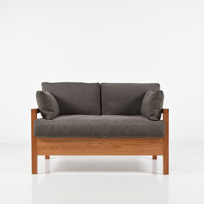 Studio lounge two-place sofa with soft dark grey upholstery on a white background.