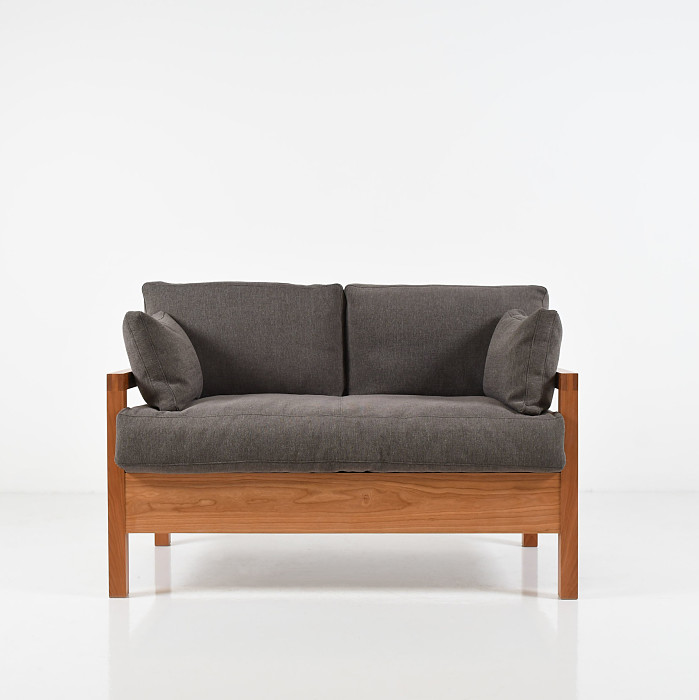Studio lounge two-place sofa with soft dark grey upholstery on a white background.